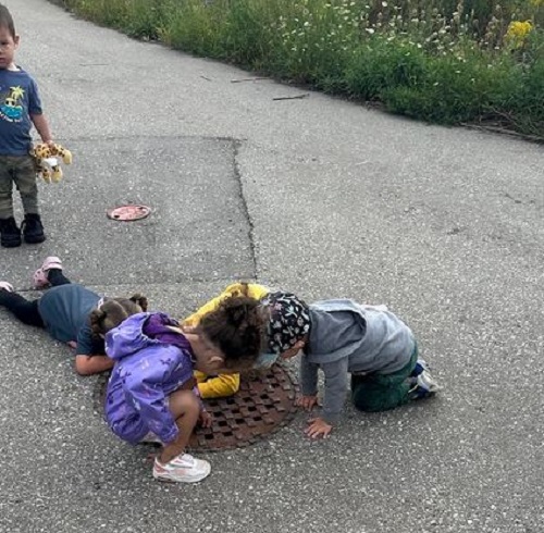 A small group of children observing a sewer.