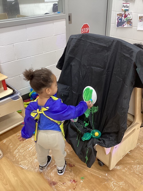 A child painting their paper plate.