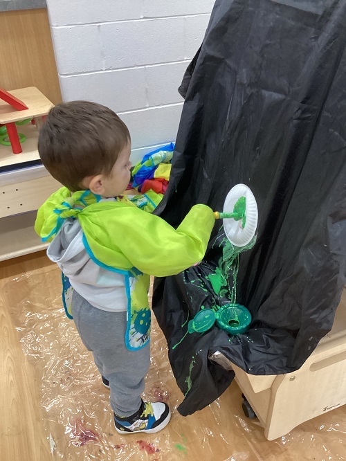 A child painting their paper plate.