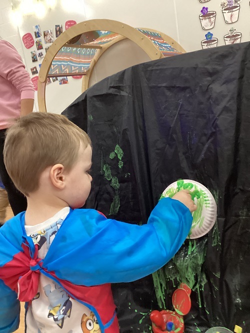 A child painting their paper plate.