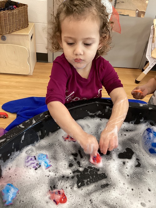 A child manipulating items in the tuff tray.