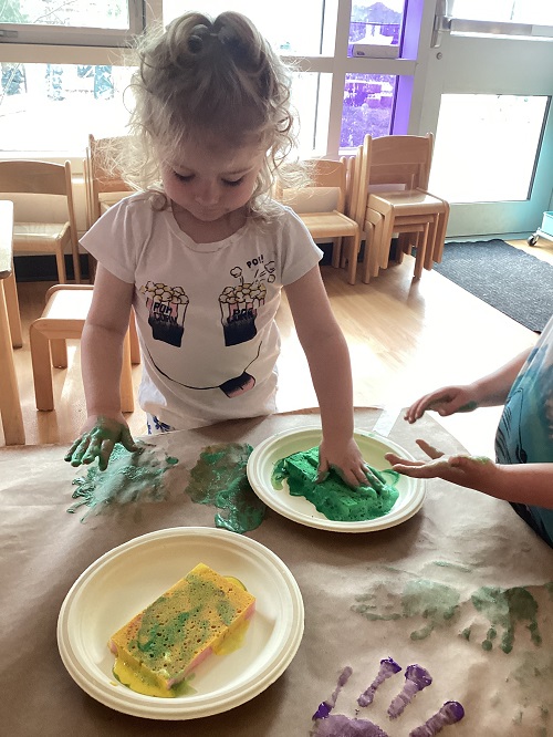 A child adding their handprint to paper