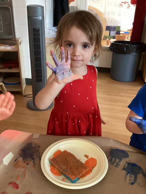 A child holding up their paint covered hand