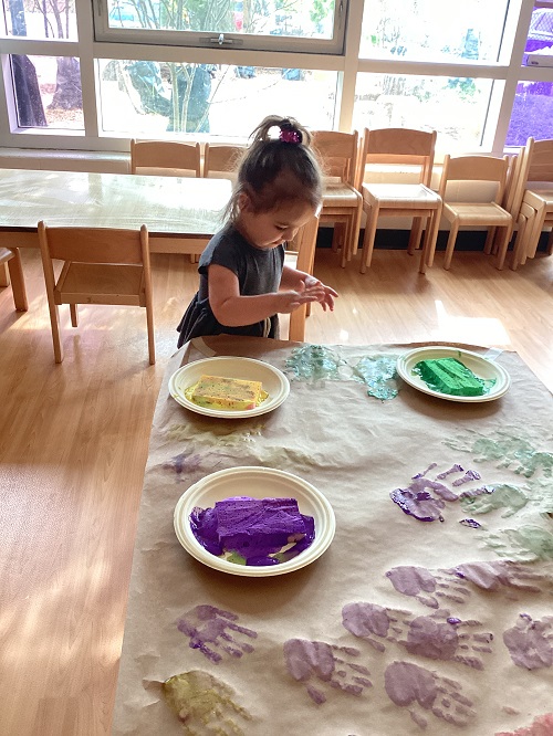 A child adding their handprint to paper