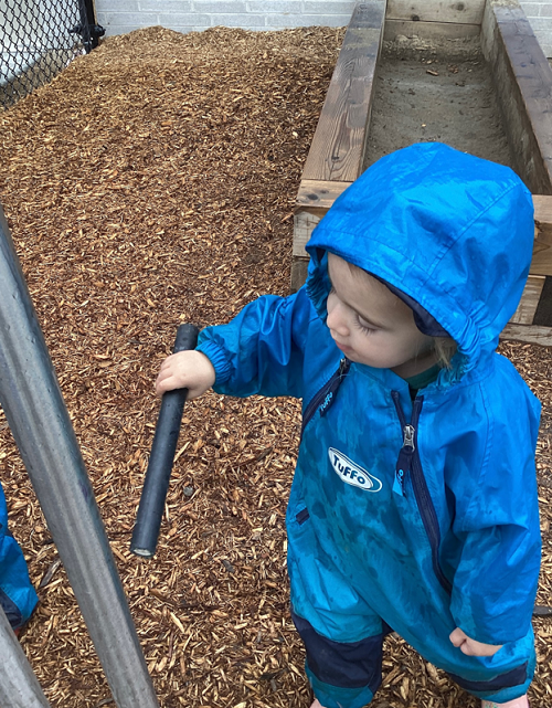 A child striking a chime tube with a mallet