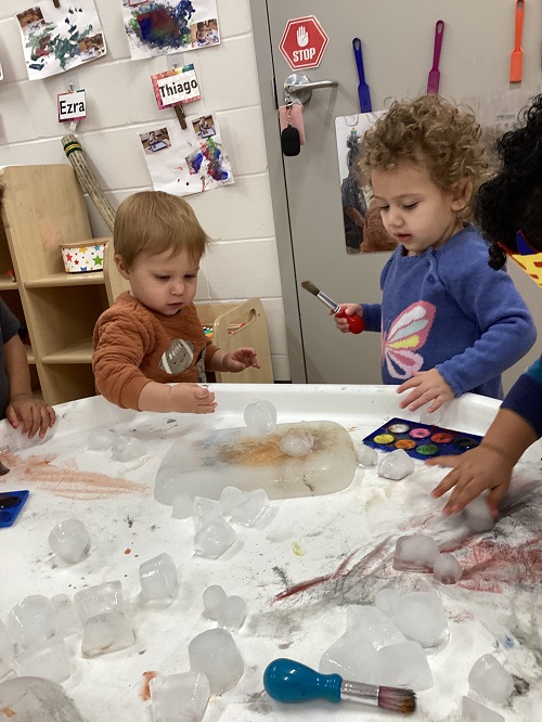 A small group of children exploring with paint and ice.