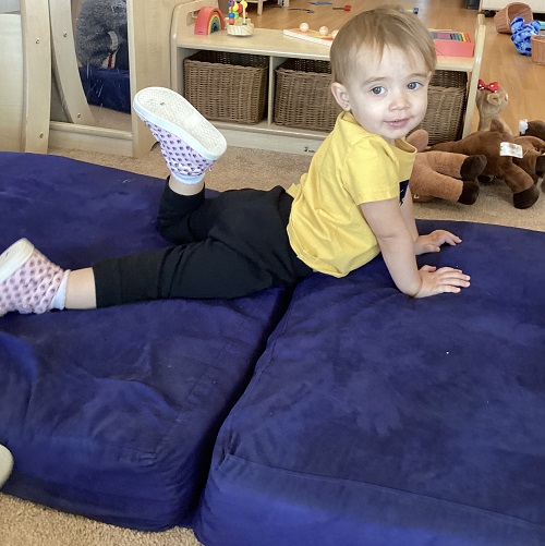 A child laying across the fold-up couch mid-play.