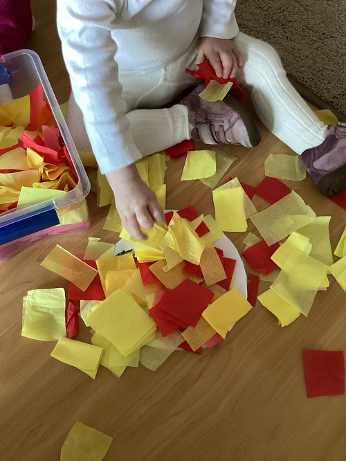 A child exploring with coloured tissue paper