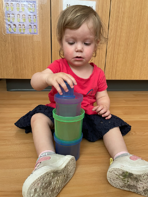 A child stacking coloured cups