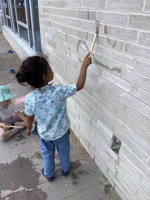 A child painting the wall with water.