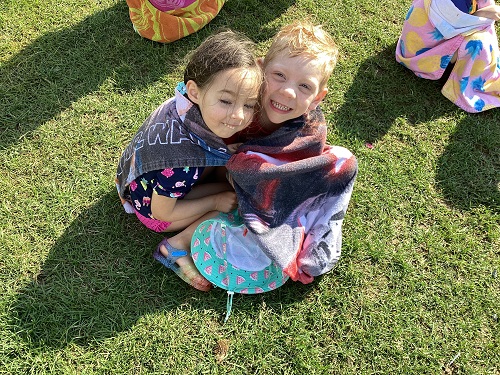 2 children in an embrace while using a towel.