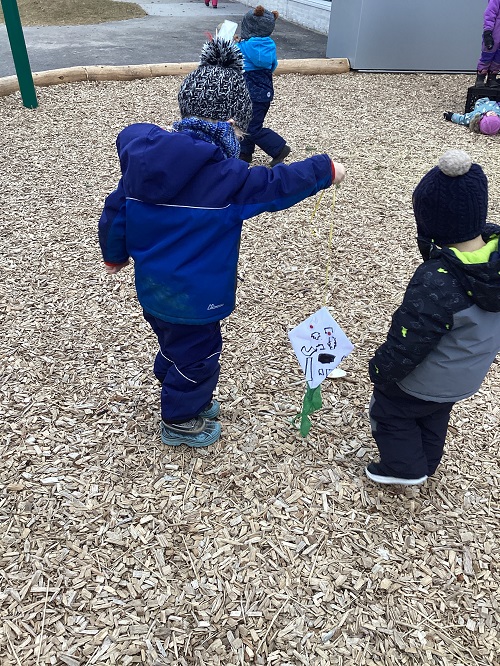 Two children are observing a kite while outdoors.