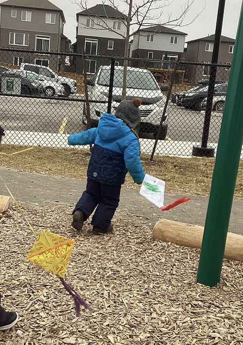 A child is holding their kite while walking.