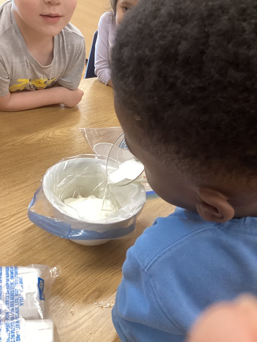 A child pouring ingredients into a bag.