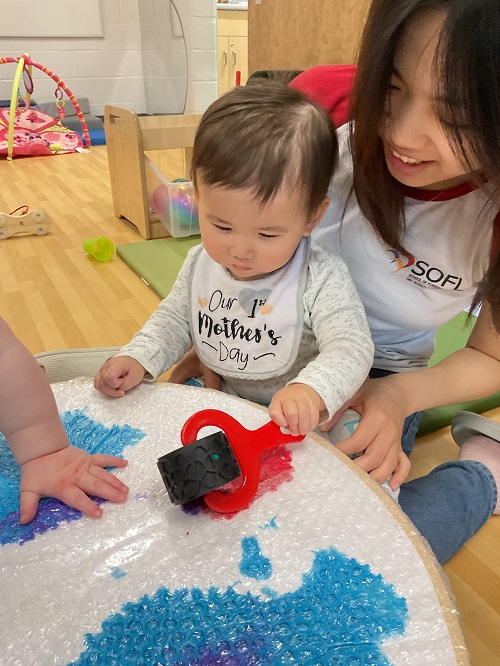 child with educator rolling paint