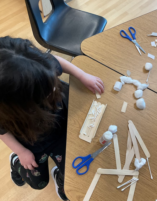 child with cotton balls and sticks