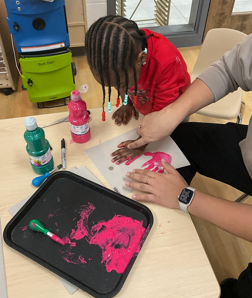 girl in red shirt maknig handprints