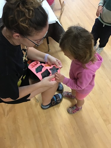 Educator and children looking at crayon moulds they made