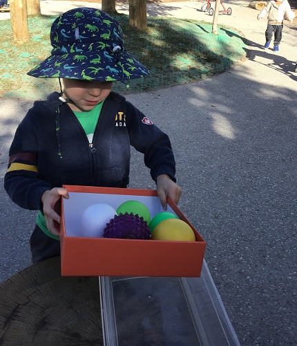 Child rolling balls in a box