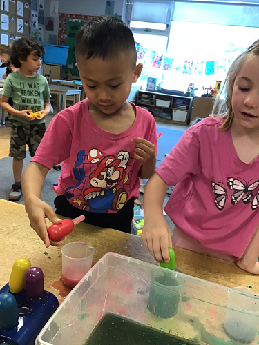Children experimenting with coloured water and oil