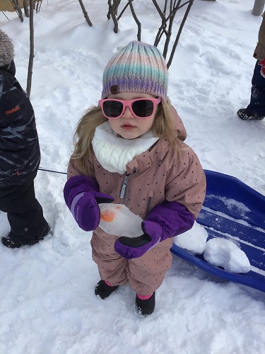 A child holding the ice egg she found on the playground