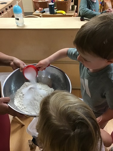 A child pouring salt into a bowl of flour