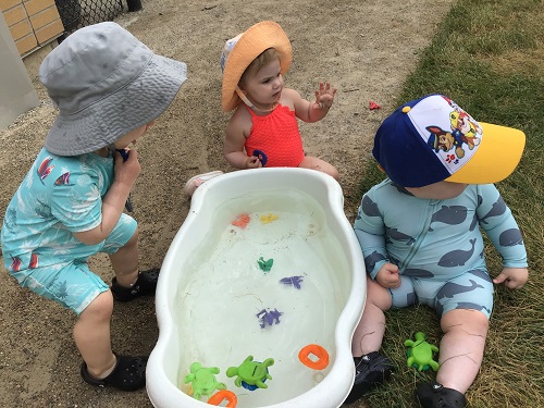 Infants exploring a tub of water with toys