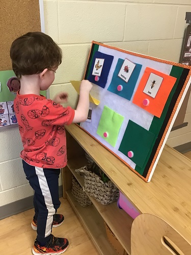 A child looking for pictures of insects under a felt sheet