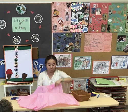 An educator playing a colour guessing game with lego blocks under a sheet