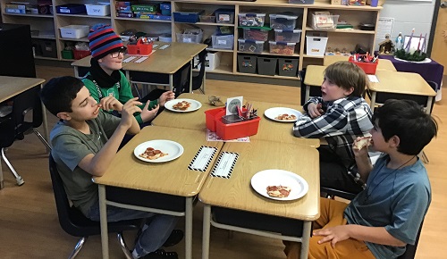 Four school age children sitting together eating the pizza they made