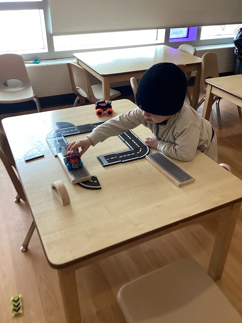 A toddler driving a car on a magnetic road