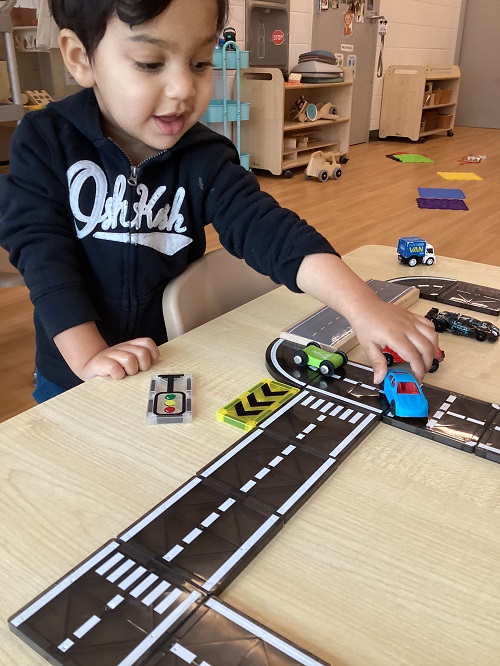 A toddler driving a car on a magnetic road