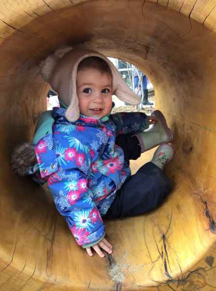 girl sitting in a large, hollow log
