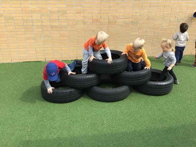preschoolers climbing in a pile of tires