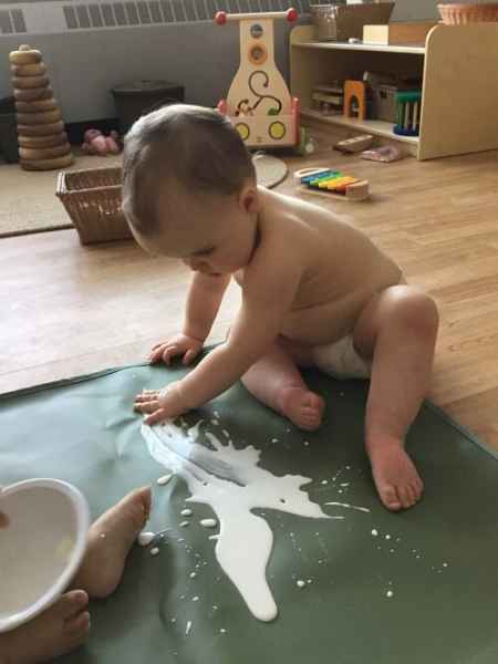 infant finger painting while sitting on the ground