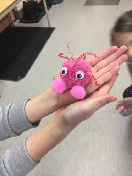 children holding their craft made of pom poms