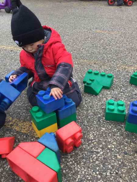 boy playing with large lego blocks outside