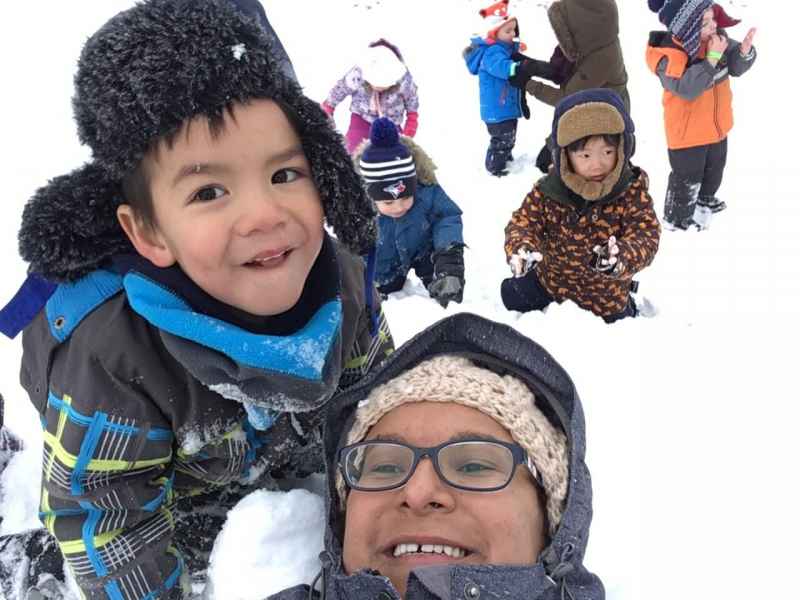 educator and children playing on a snow hill