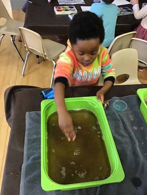 child with green germ bucket