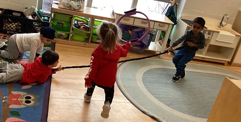 3 children holding a long stick one child holding a hoop