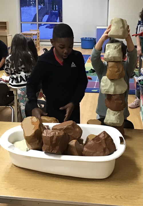 children building a tower with tan and brown foam blocks