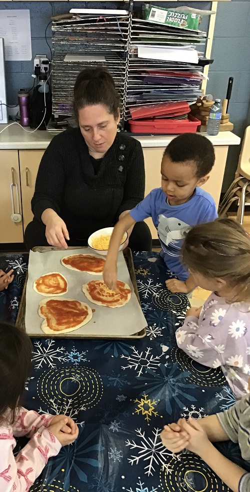 children adding toppings onto a pizza