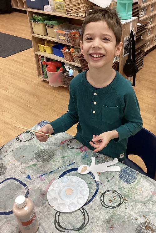 child sitting at a table making a paper version of themself