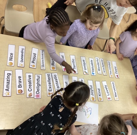 children at a table full of kind words written on papers