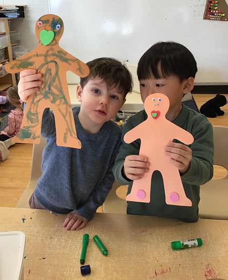 children holding up a person cut out that they decorated