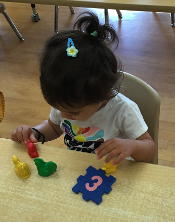 child playing with foam numbers and counting items