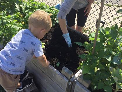 child and educator planting a garden