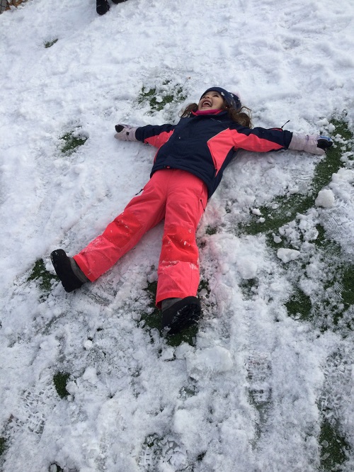 girl creating a snow angel