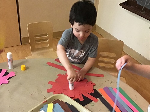 child gluing paper down onto paper