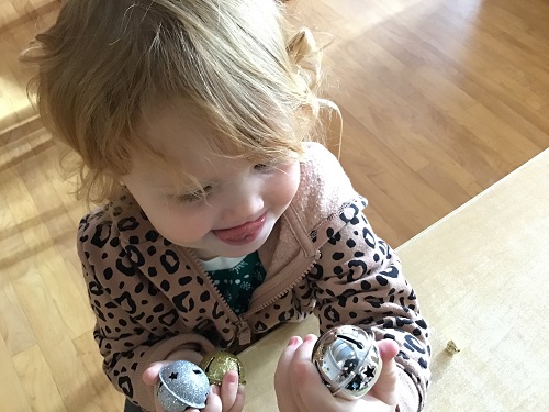 A preschooler is holding some jingle bells.